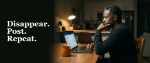 Business owner sitting at a kitchen table late at night, hesitating in front of an unfinished social media post on his laptop, illustrating the visibility cycle of disappearing and posting out of guilt.